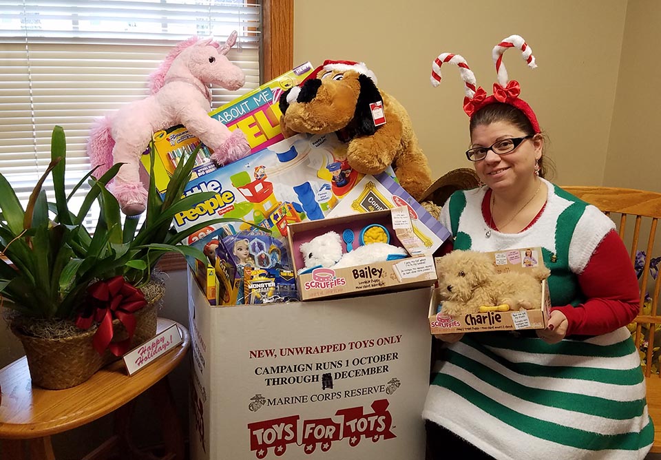IQ employee April Rak displaying the toys collect for Toys for Tots in 2016.