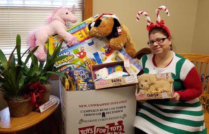 IQ employee April Rak displaying the toys collect for Toys for Tots in 2016.